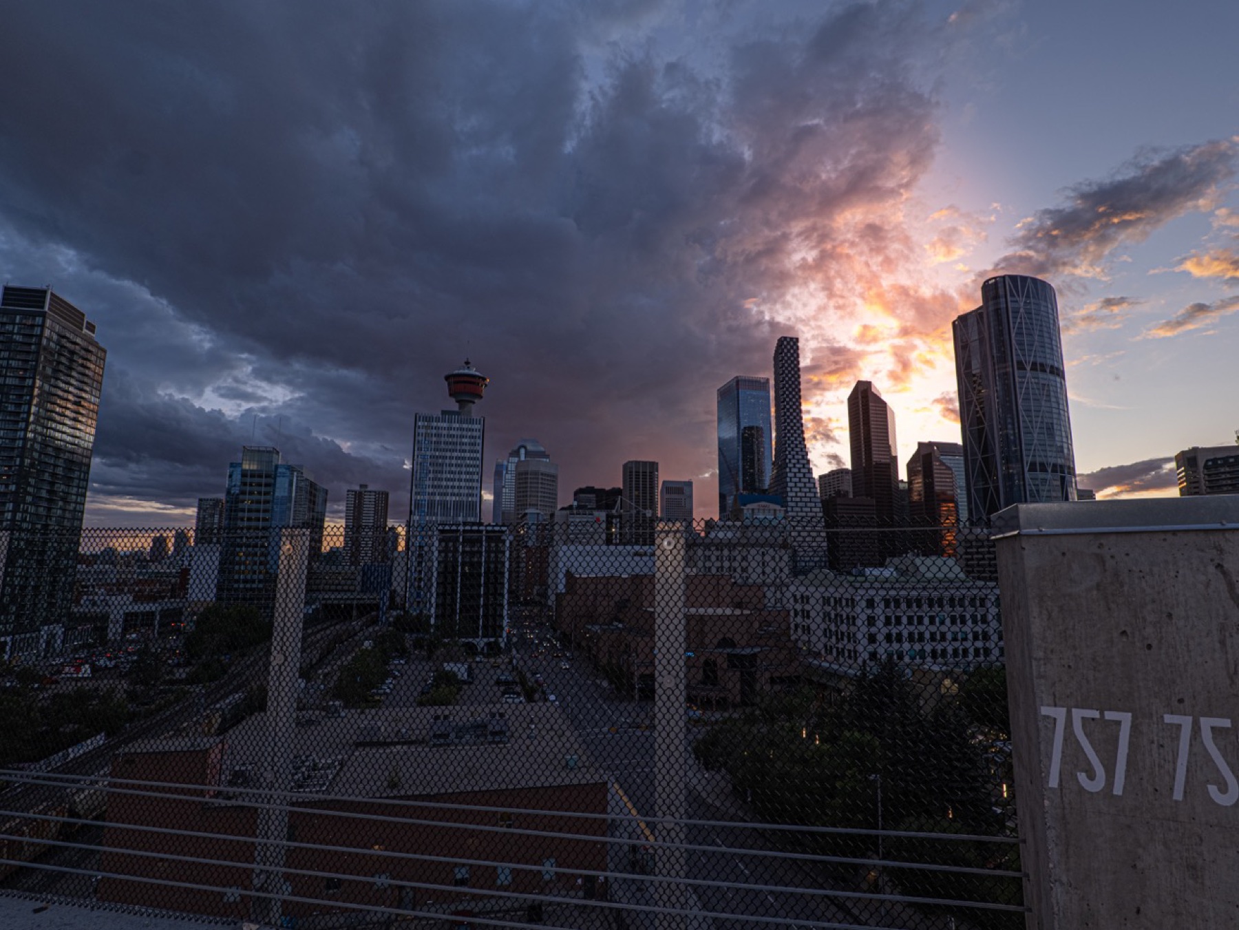 Calgary skyline from a platform at sunset under storm clouds.