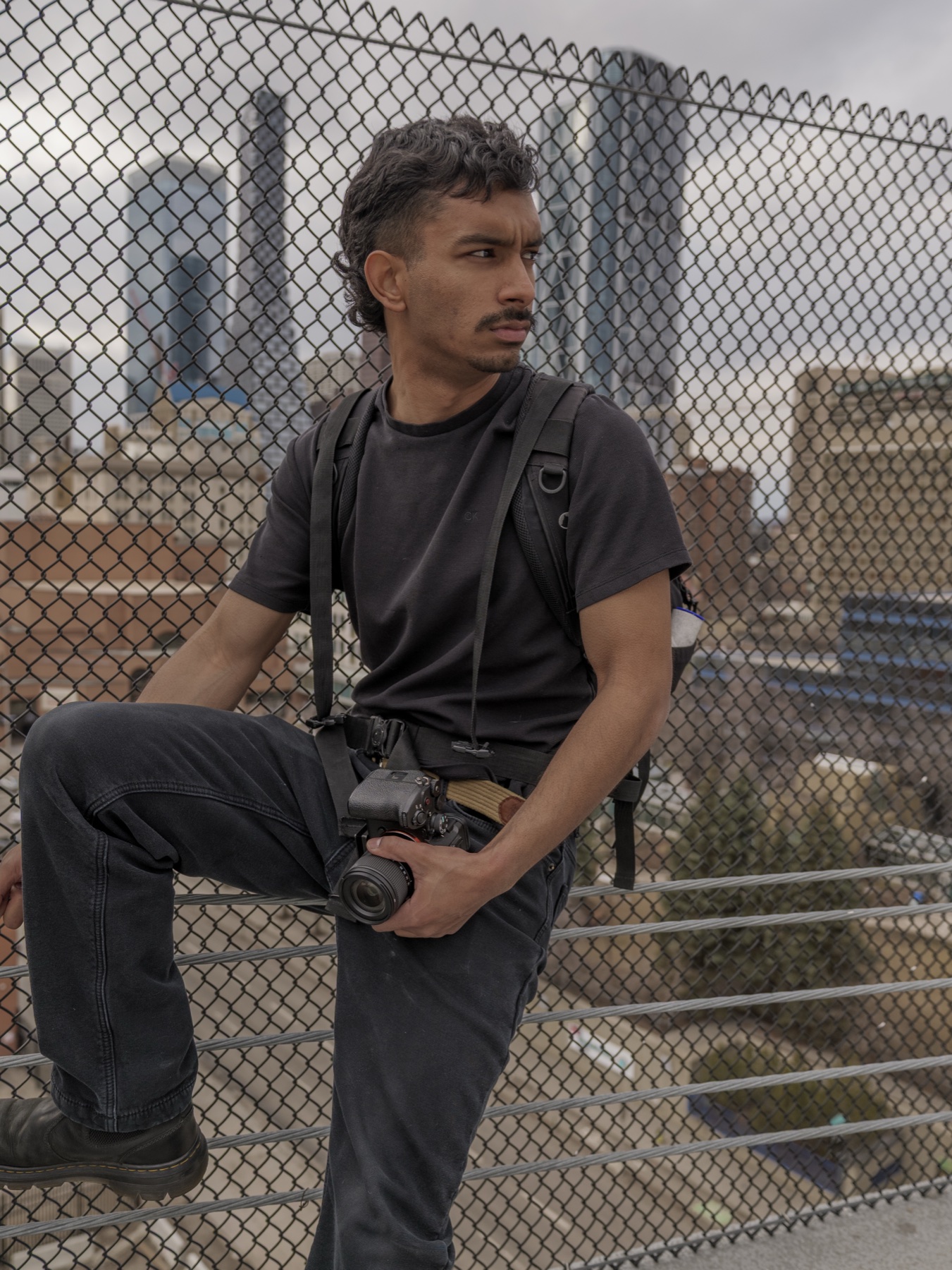 Jose seated by a rooftop fence with a camera.