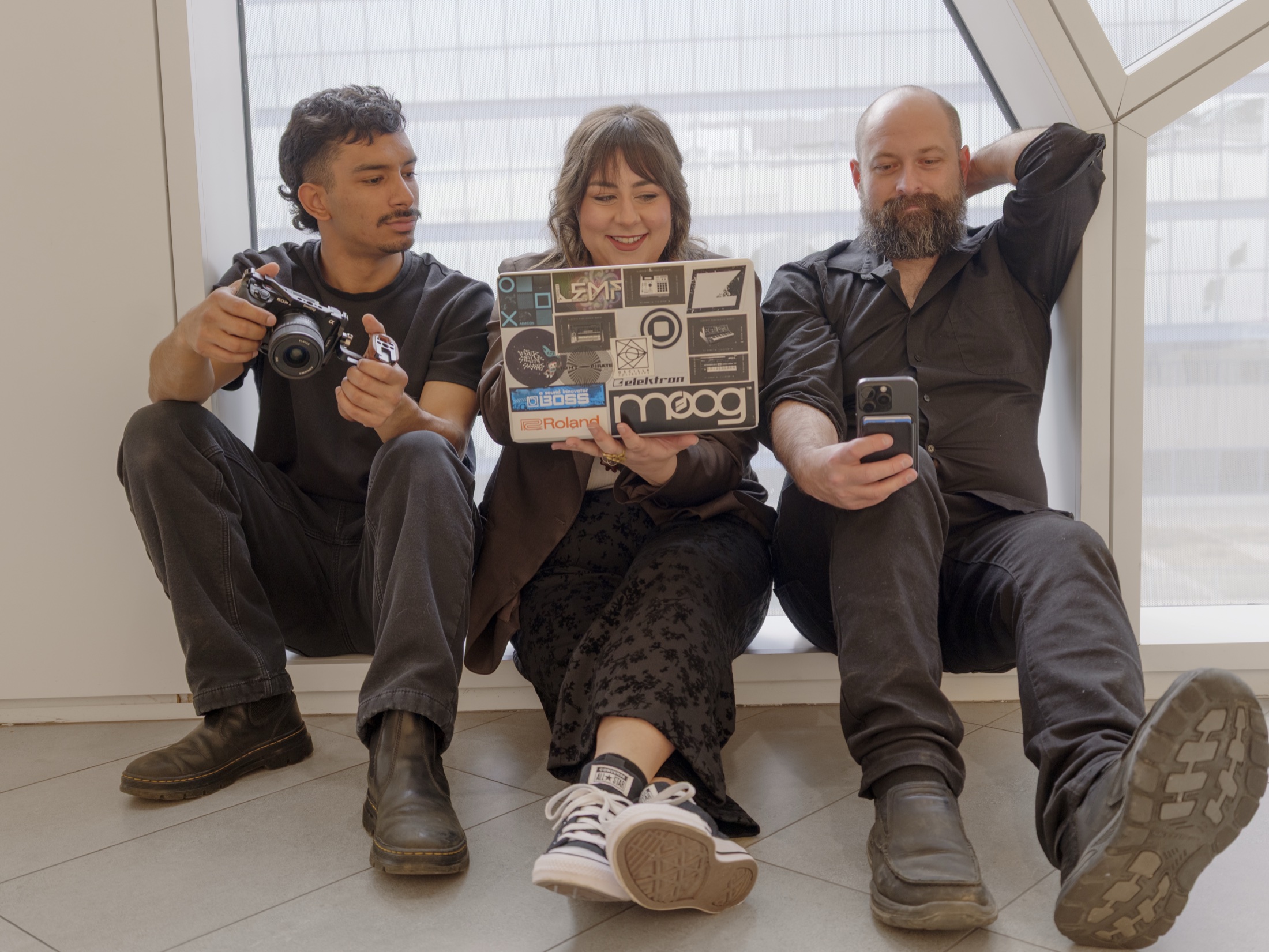 Kia, Ayrielle, and Jose seated together with cameras and a laptop.